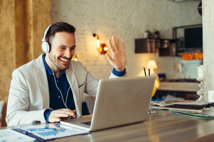 Man waving at computer screen