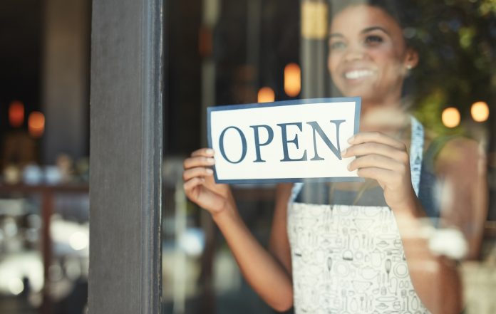 Shop owner putting up open sign