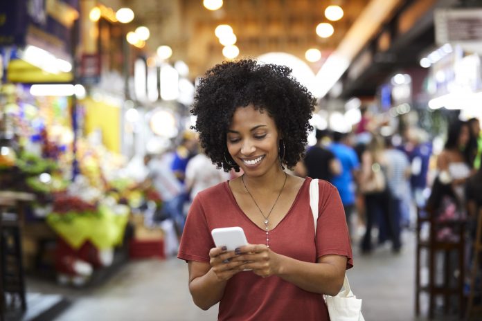 Smiling woman looking at her phone while shopping