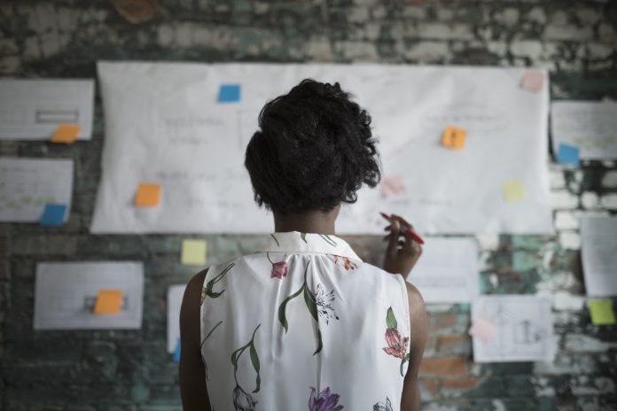 A woman looking at a white board with notes